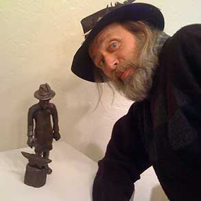 An artist poses next to his self portrait sculpture