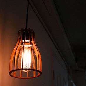 A hanging lightbulb fixture made with lazercut wood at a hackerspace in Hong Kong