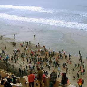 A flashmob appears at a California beach to walk a mandala as the tide rolls in